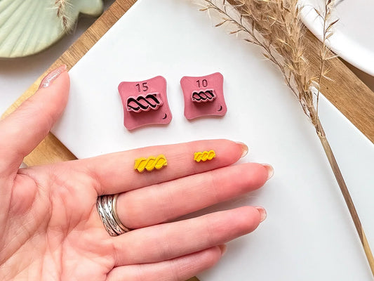 Fusilli pasta micro cutter set with 2 clay cut outs in a hand for scale
