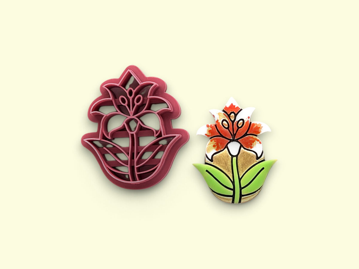 A floral polymer clay cutter and a matching hand-painted flower earring on a pale cream background.