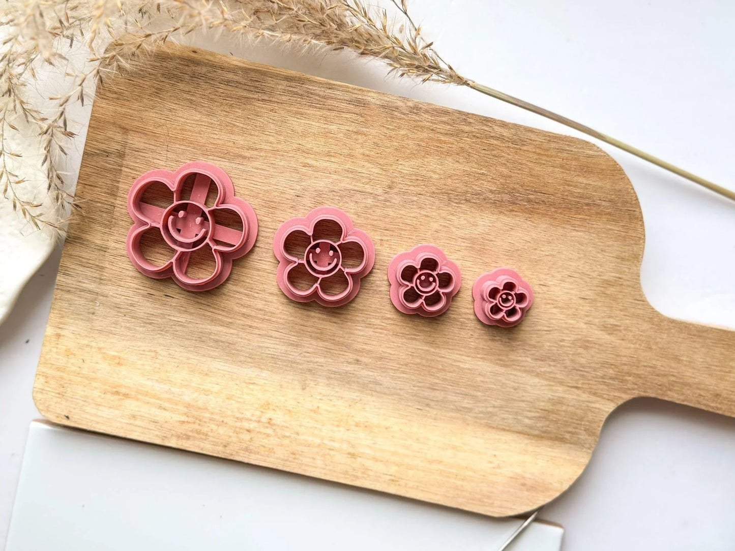 4 sizes of groovy daisy polymer clay cutter. 5 petal daisy shape with simple smiling face in the middle.