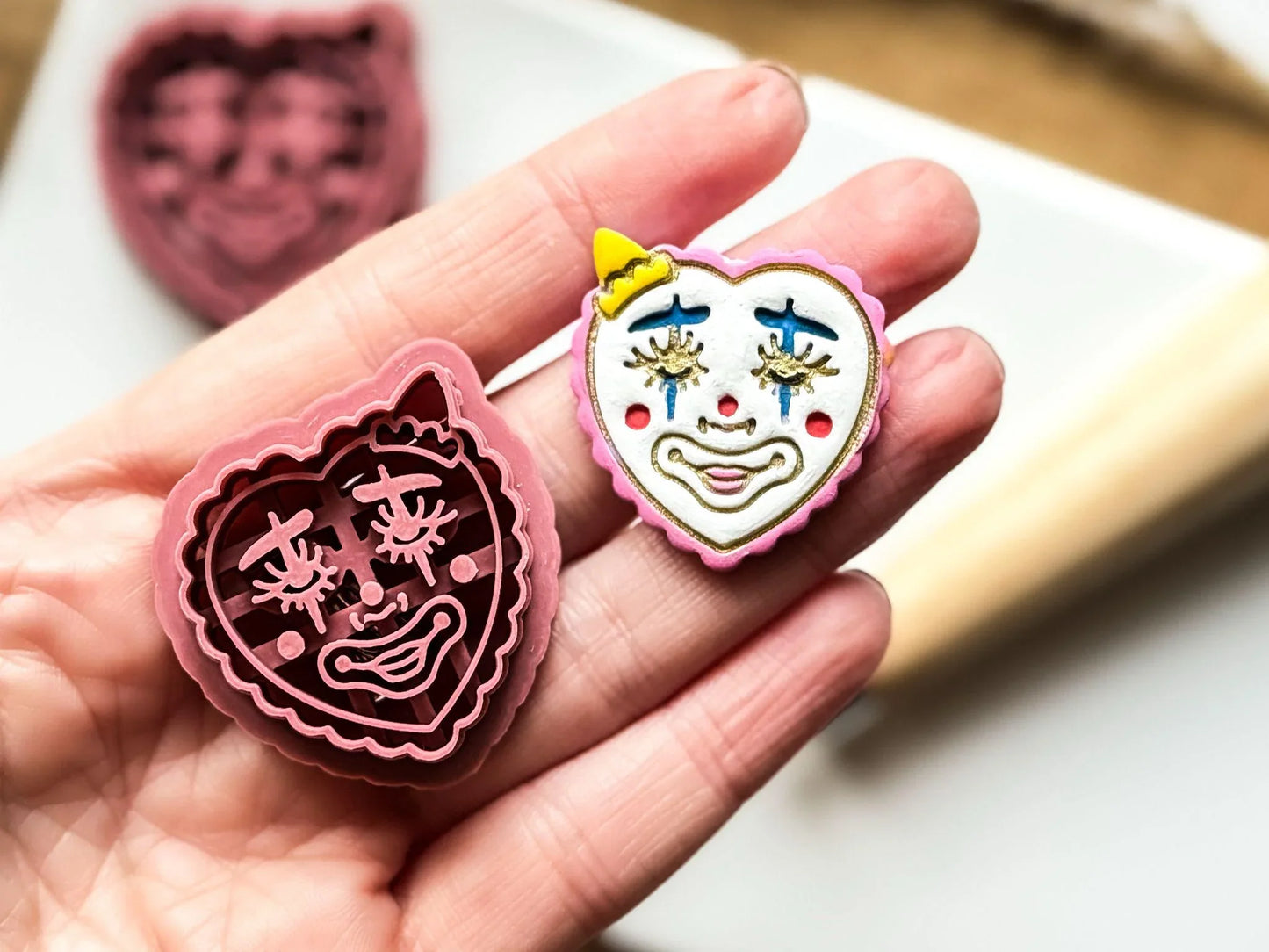 Clown face clay cutter with imprint details in hand for scale