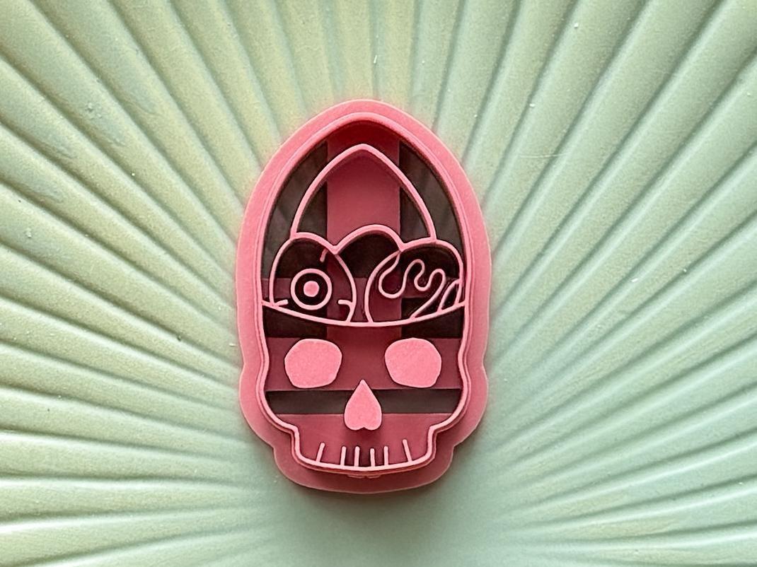 Close up image of creepy gothic easter egg basket clay cutter in pink on a green plate