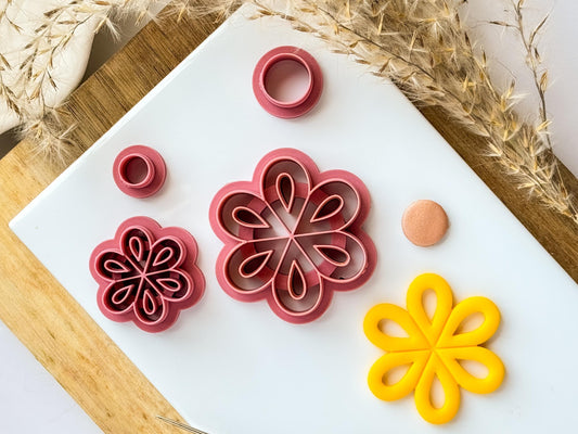 Several sizes of outline flower clutter for polymer clay on white tile