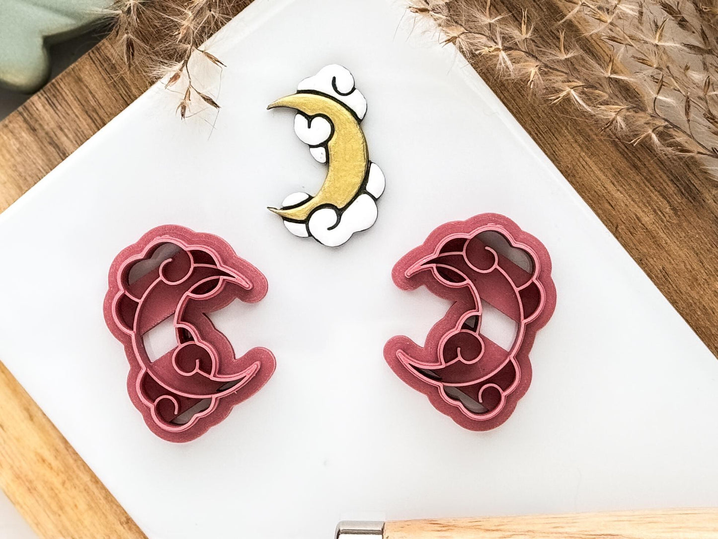 Moon and clouds shaped polymer clay cutter set in dark pink on a white tile