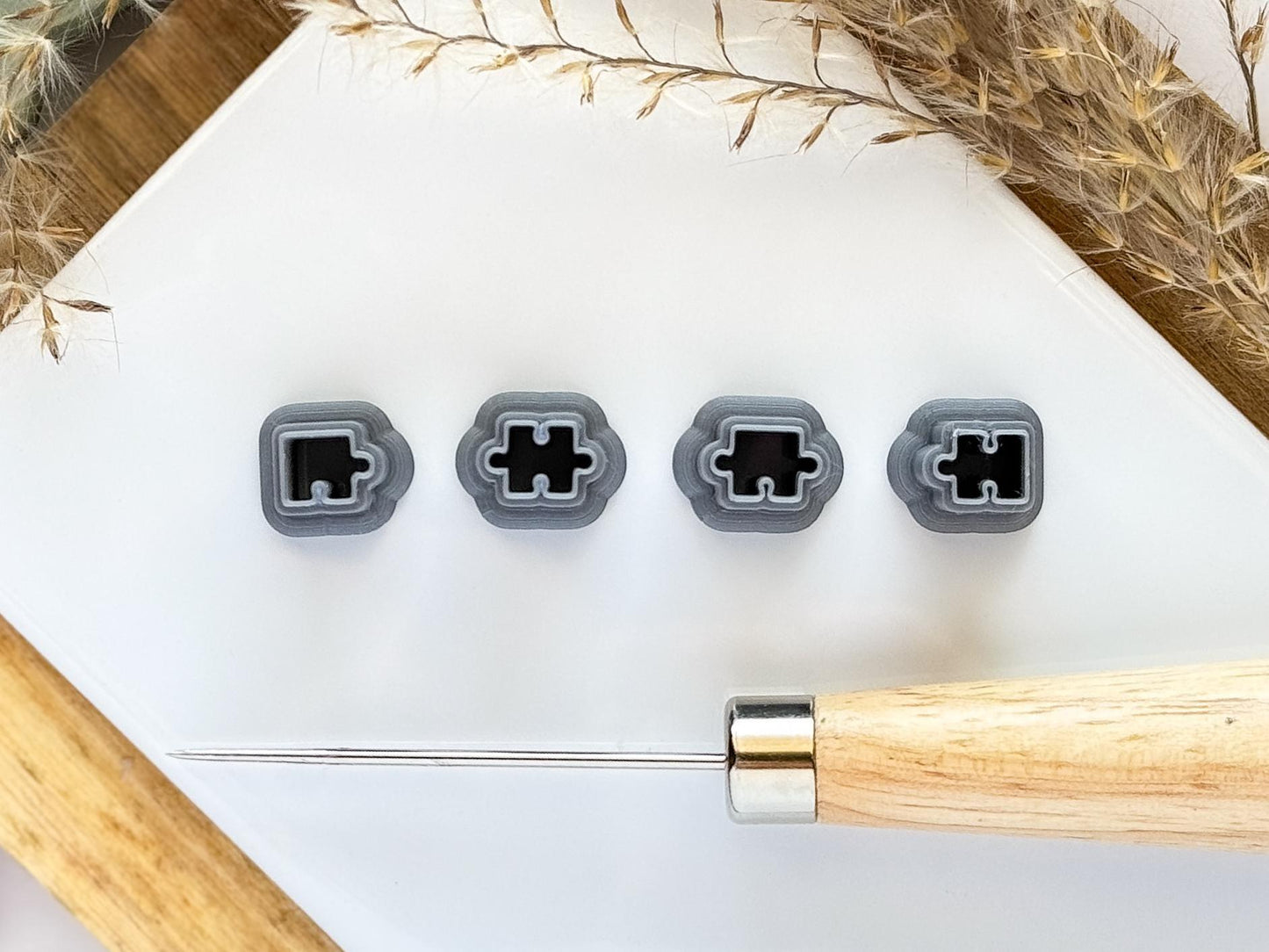 Micro clay cutter set of 4 puzzle pieces in silver on a white tile
