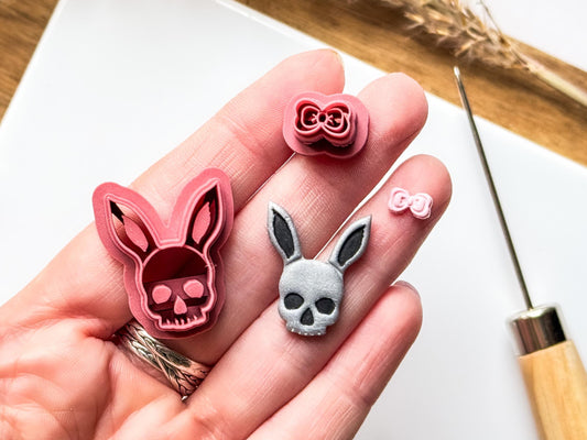 Gothic Easter bunny clay cutter in pink material with silver and black clay cut out. Both being held in a hand to show the scale of the small cutter and close up details.