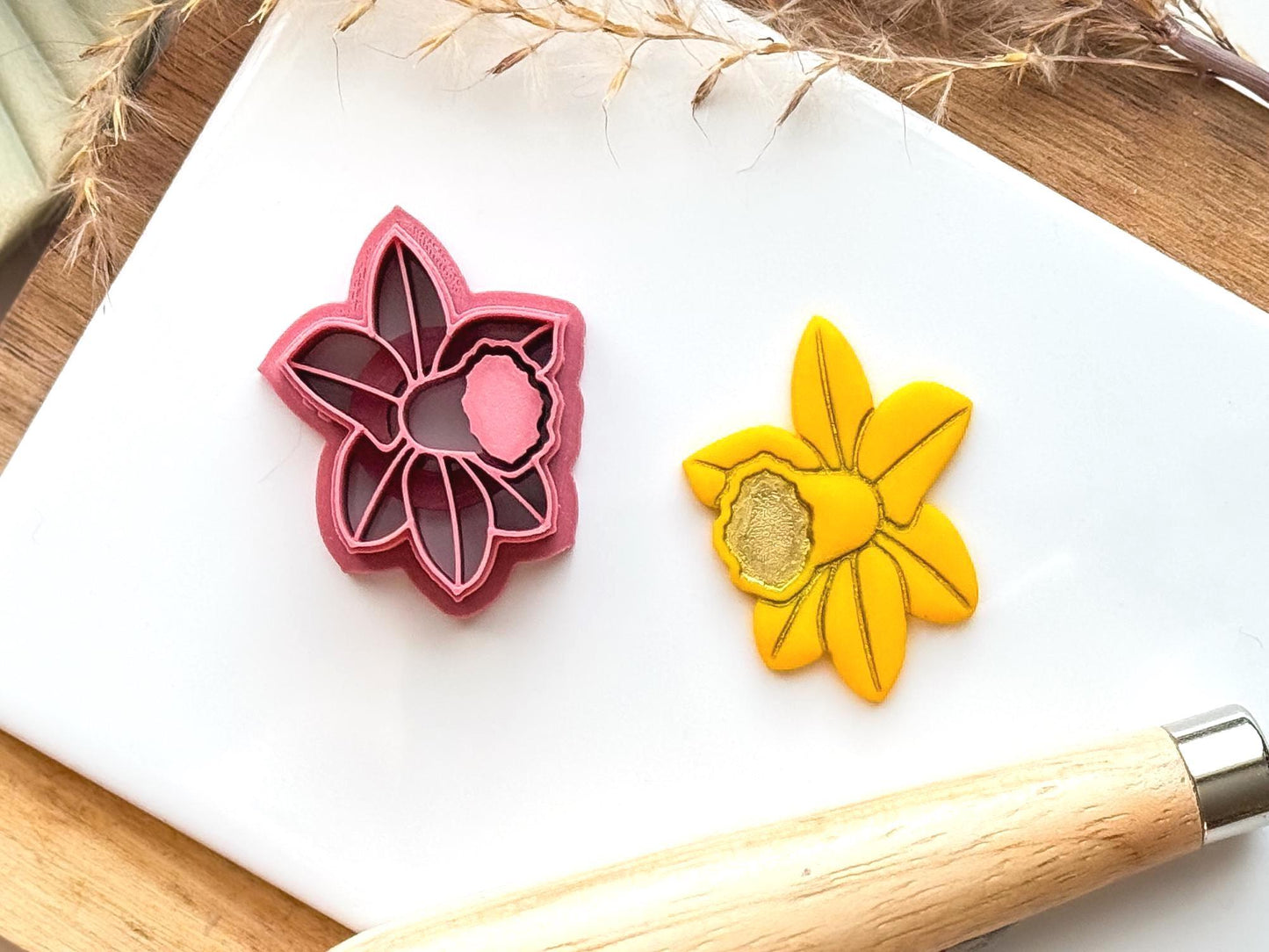 daffodil polymer clay cutter in pink with sample cut out clay piece on a white tile