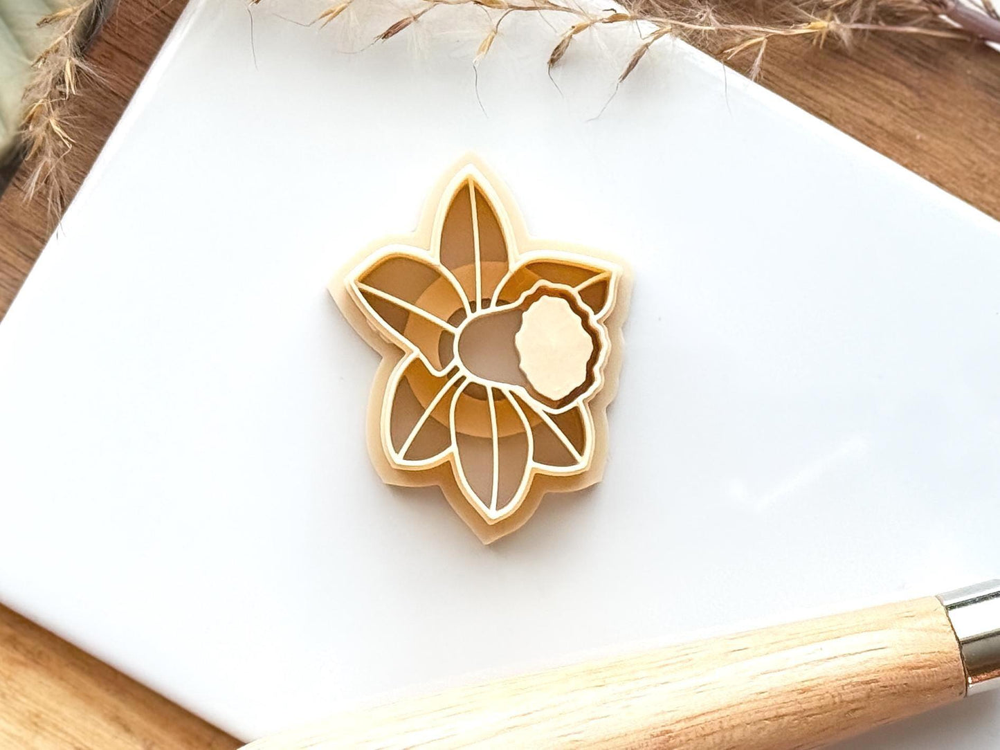 Beige spring flower clay cutter on a white tile