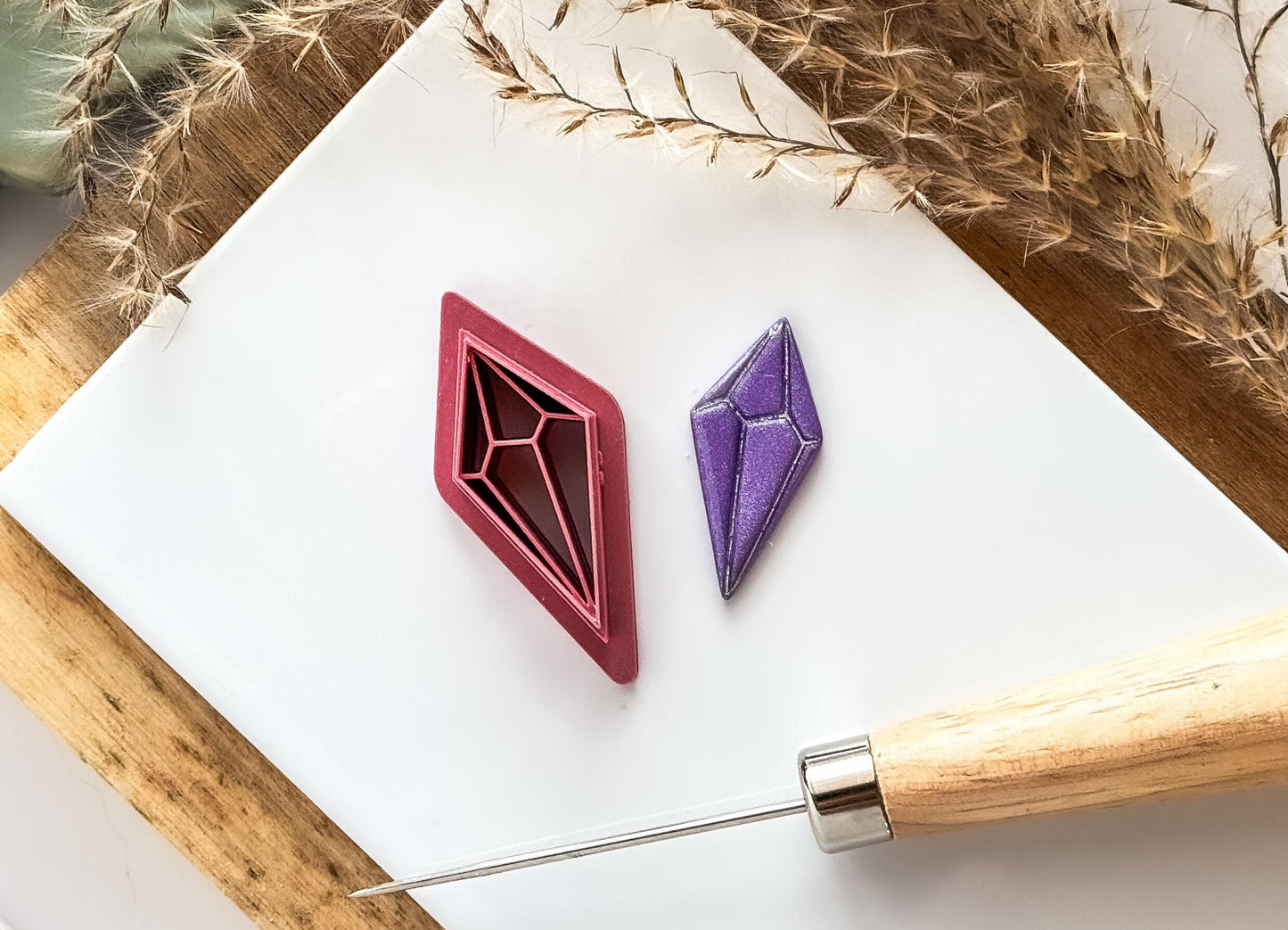 Pointed crystal clay cutteron white tile with clay tools and purple cut out clay