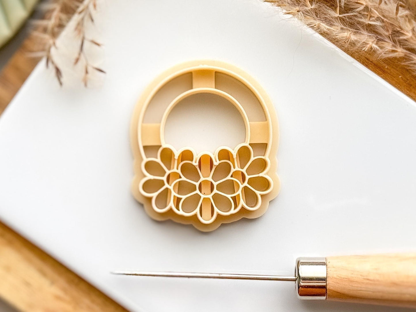 Beige colured plastic clay cutter on a white tile with a clay tool
