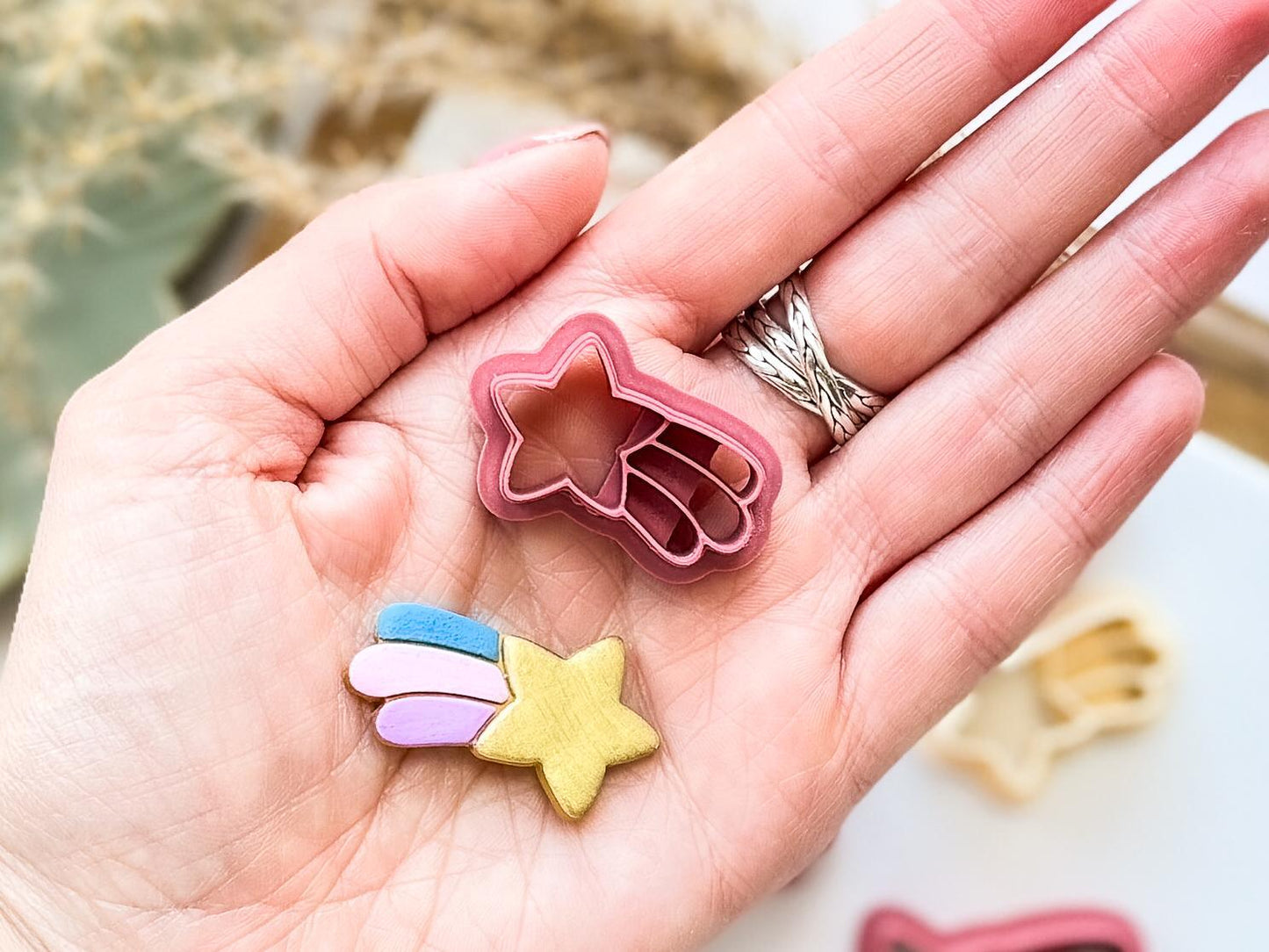 shooting star clay cutter being held in hand with a sample cut out to show scale