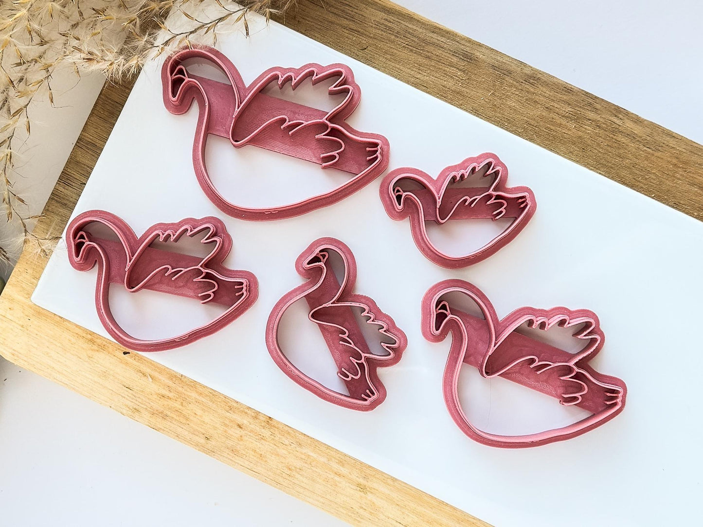 Top view of various swan clay cutter sizes on a white tile used for baking clay