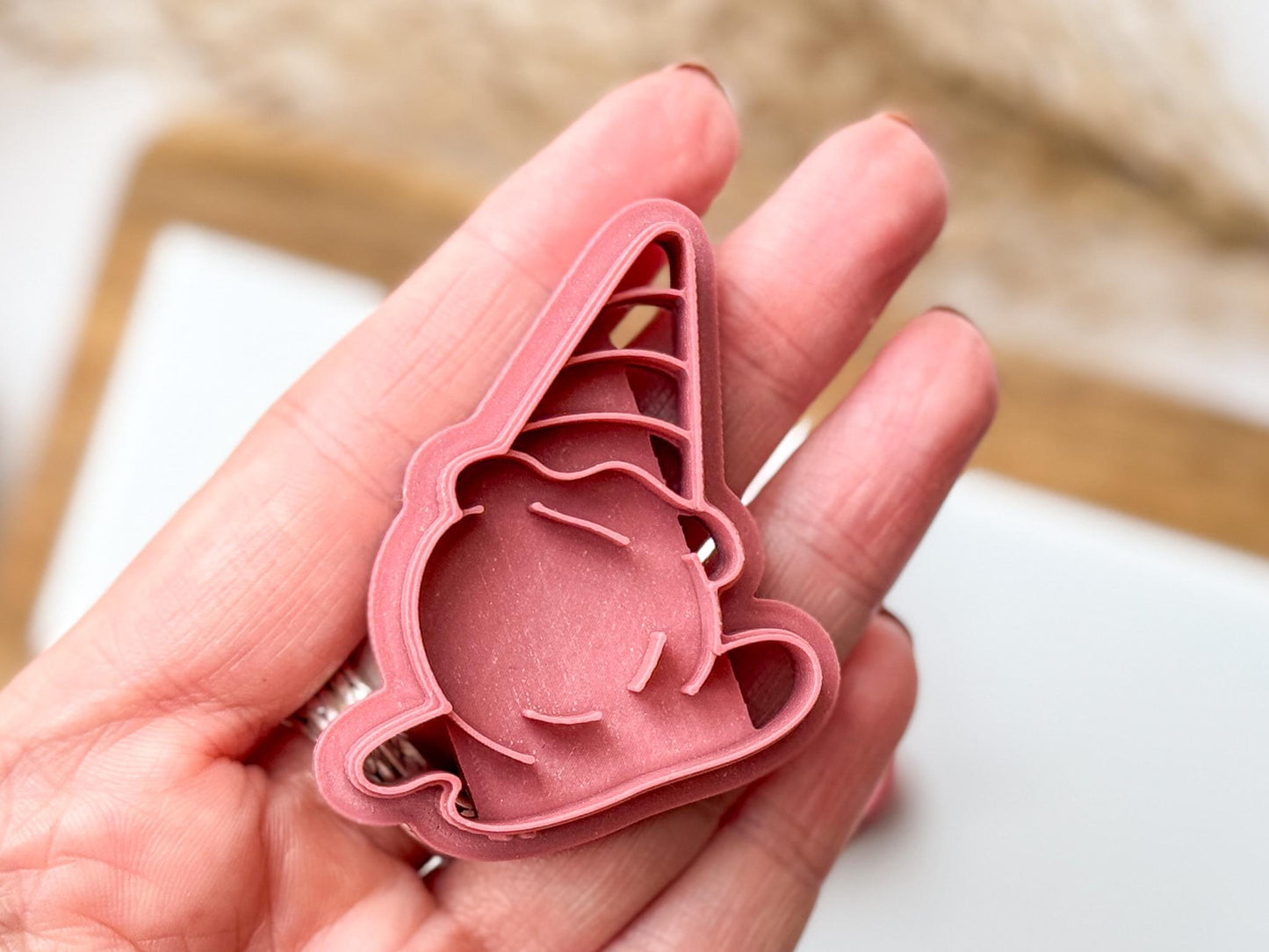 Close up of ice cream clay cutter being held in a hand for scale