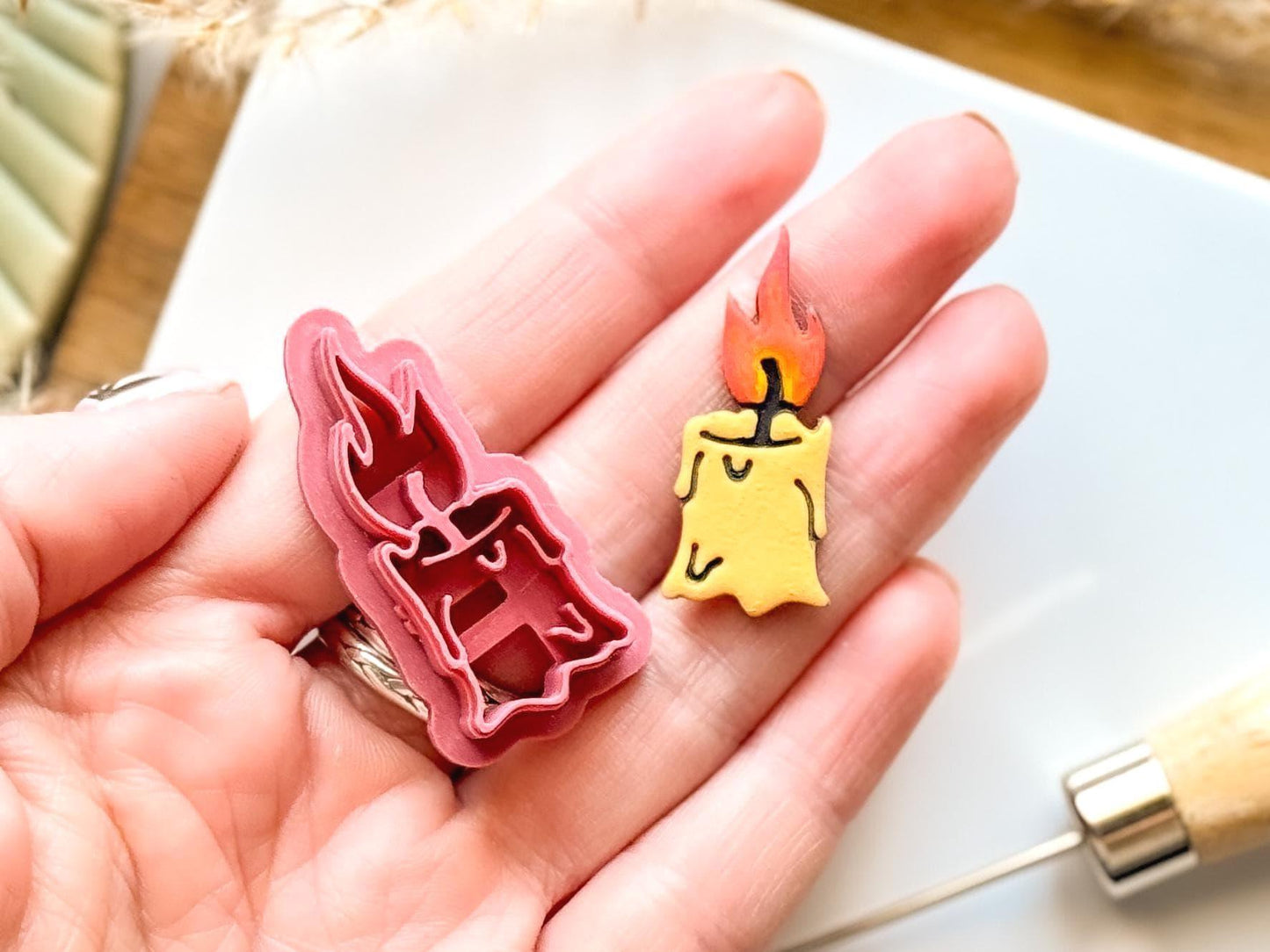 Candle clay cutter and polymer clay sample piece being held in a hand for scale