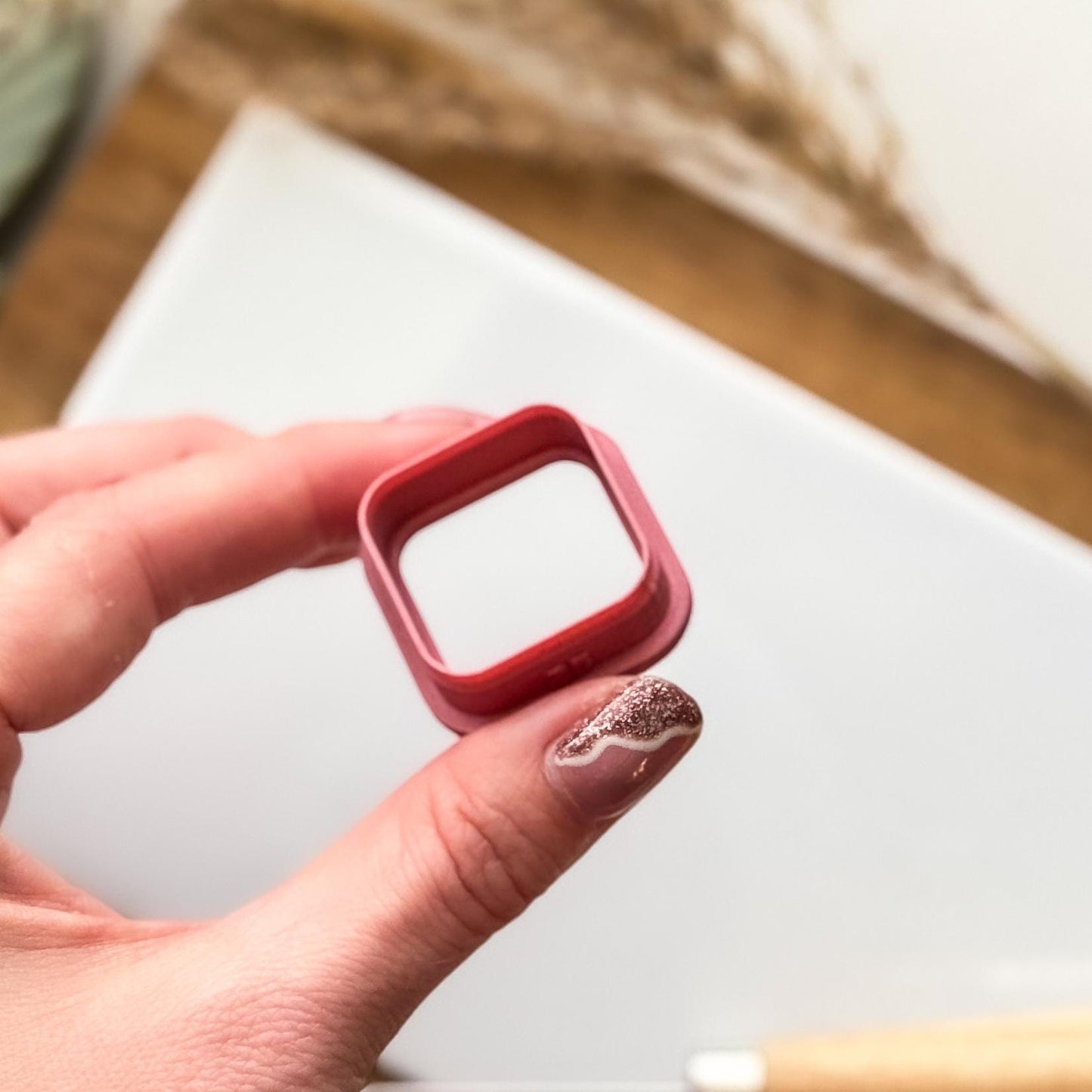 Tilted side view of a rounded corner square clay cutter being held