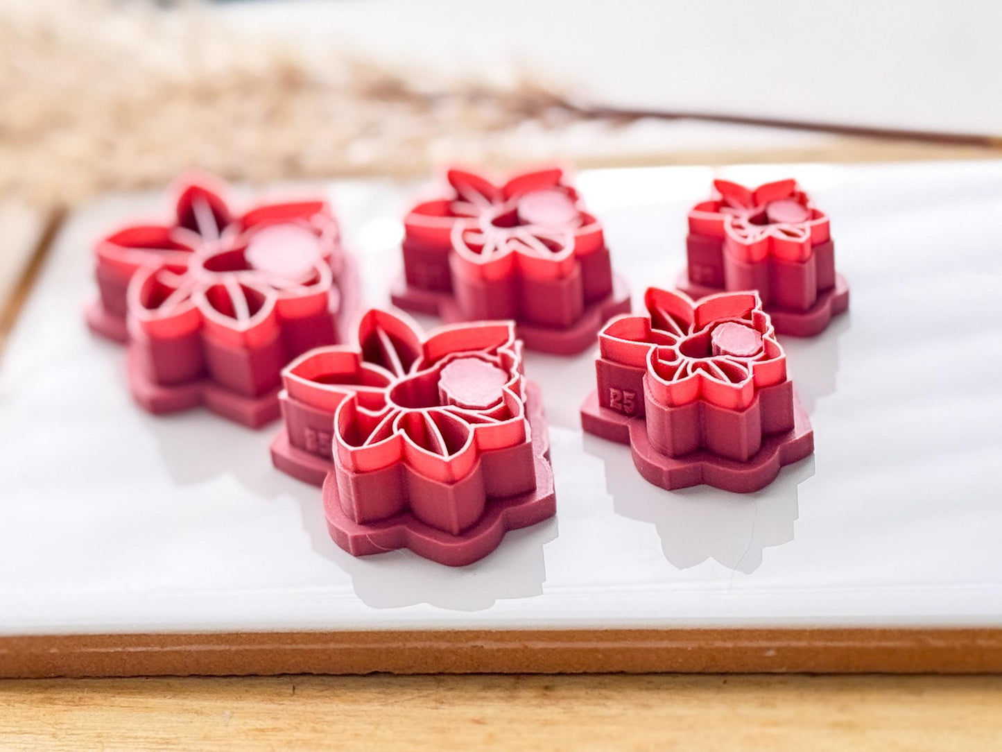 side view of 5 differently sized clay cutters in the shape of a daffodil. image showing the depth of the stamp details and sharpness of the cutting edge