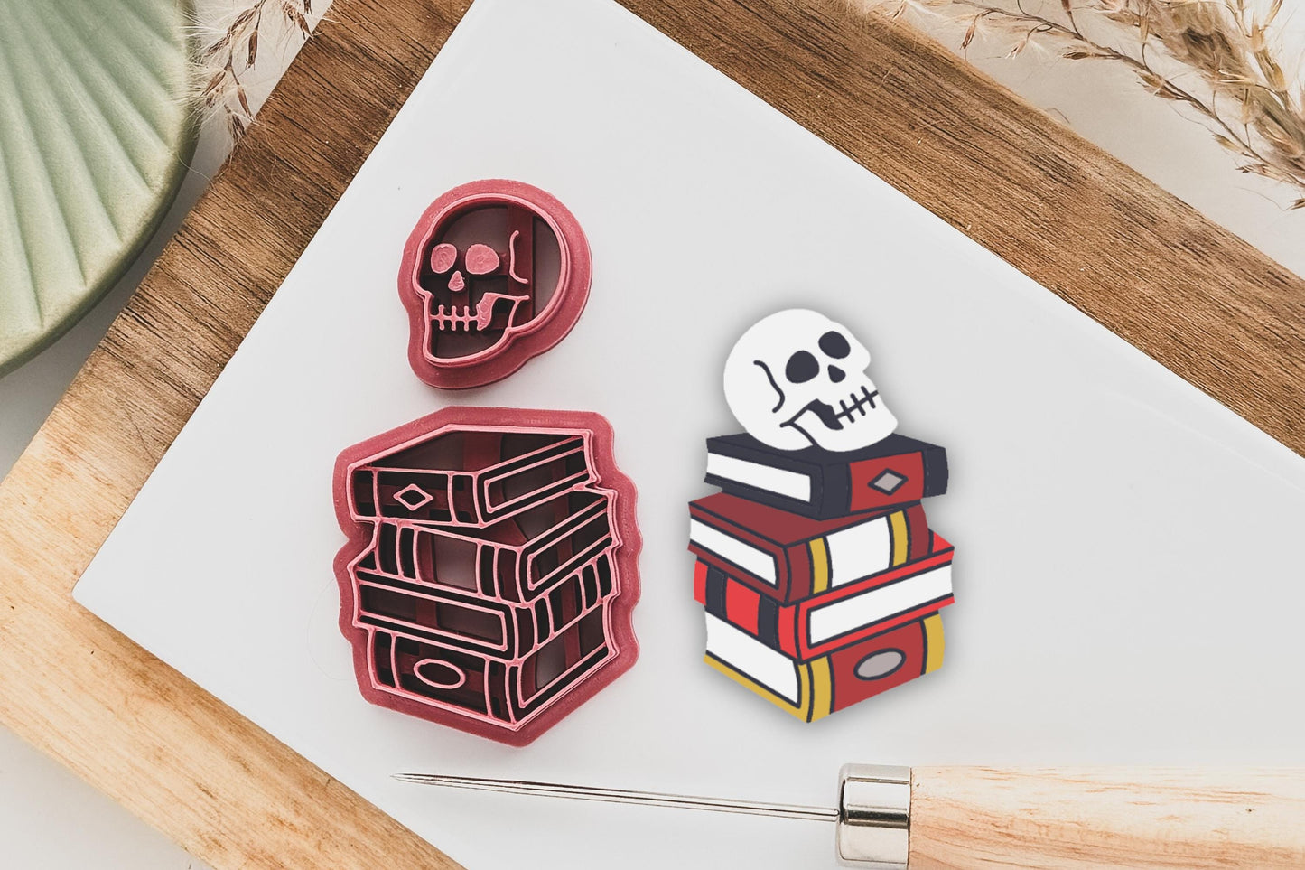 polymer clay cutter in the shape of a stack of books with labels and cover details with a separate side facing skull cutter.
