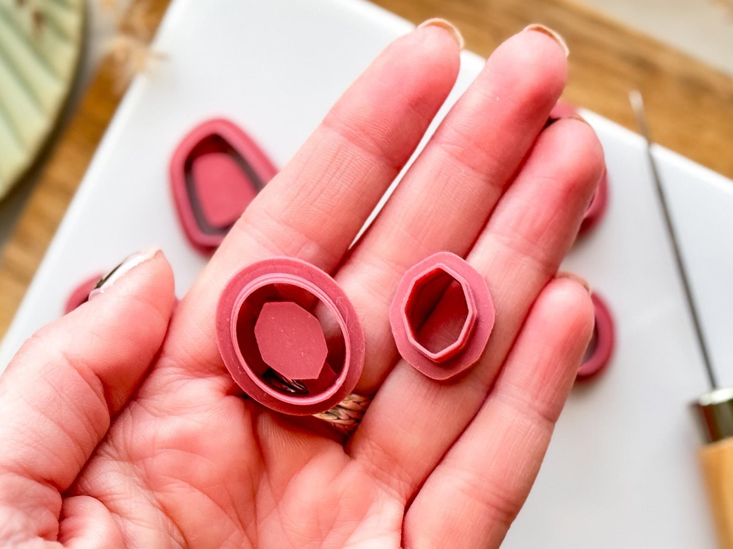 Hand holding a pink oval inlay clay cutter and gemstone shaped center cutter