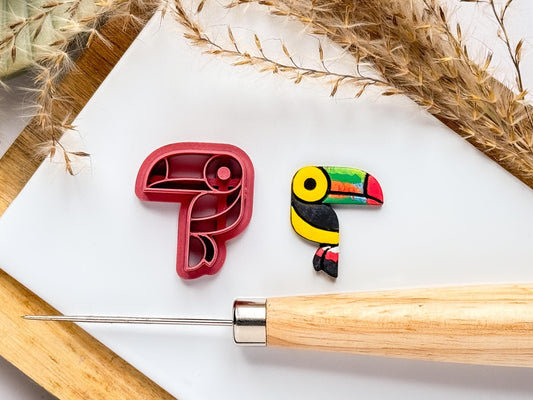 Toucan tropical bord ploymer clay cutter on a white tile with a clay cut out sample painted in brihgt colours.