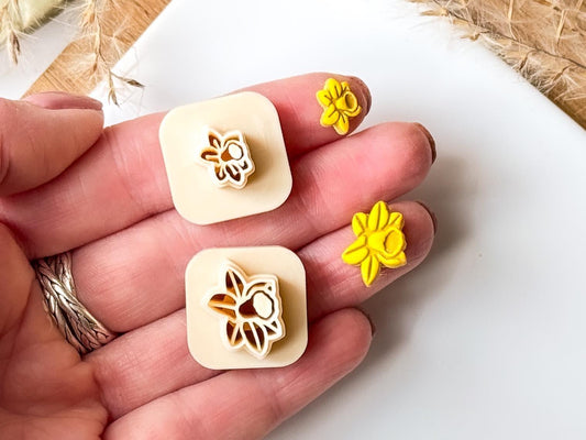 Beige micro flower cutter set in daffodil shape being held in a hand to show scale.
