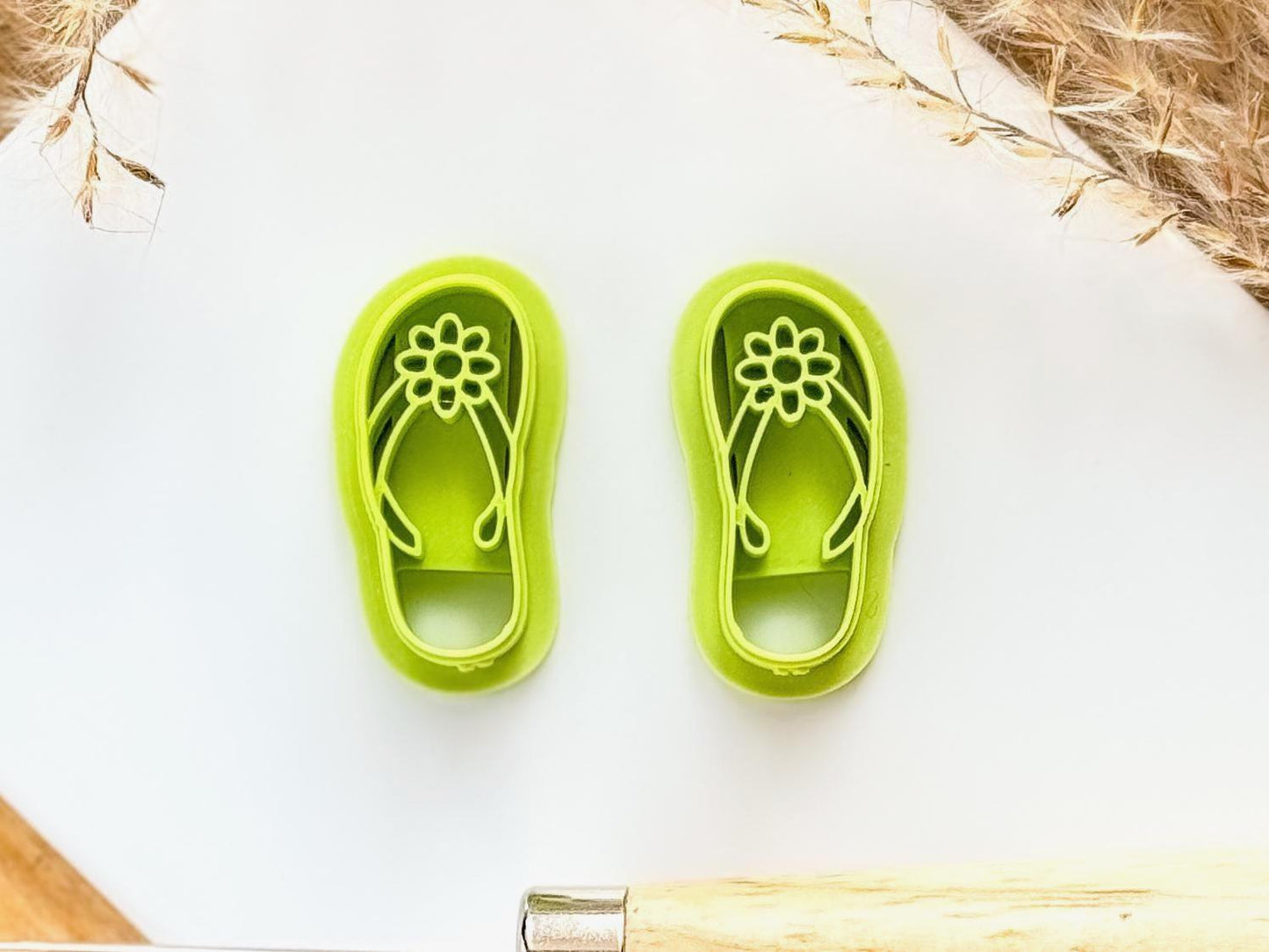 mirrored pair of flip flop sandal clay cutters with straps and flower detail in bright green