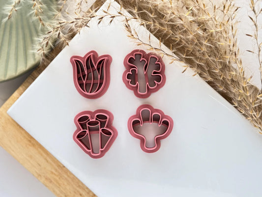 close up of 4 pink coral and seaweed clay cutters on a white tile
