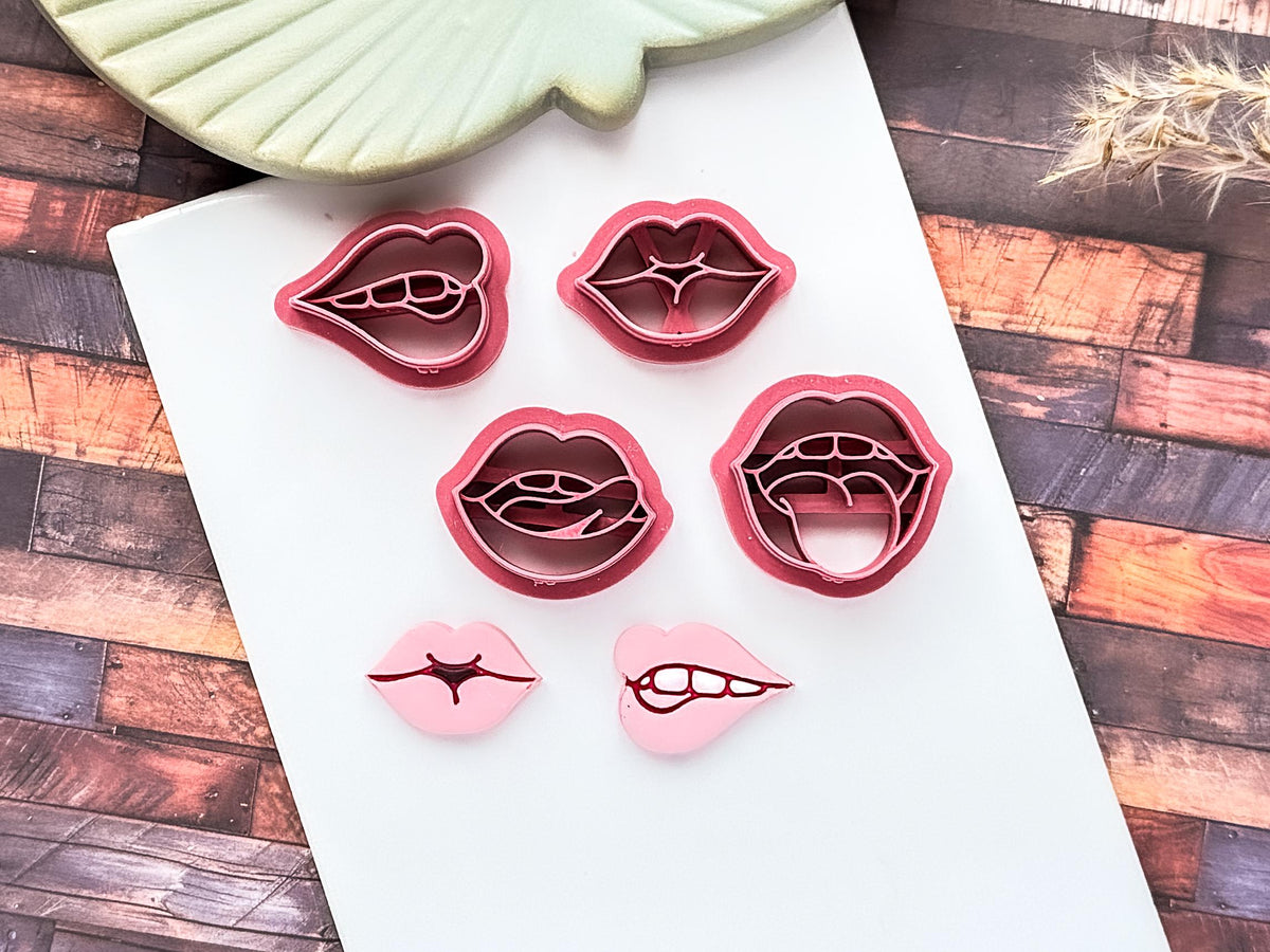 set of 4 pink lip shaped polymer clay cutters with sample polymeer clay cut outs on a white baking tile.