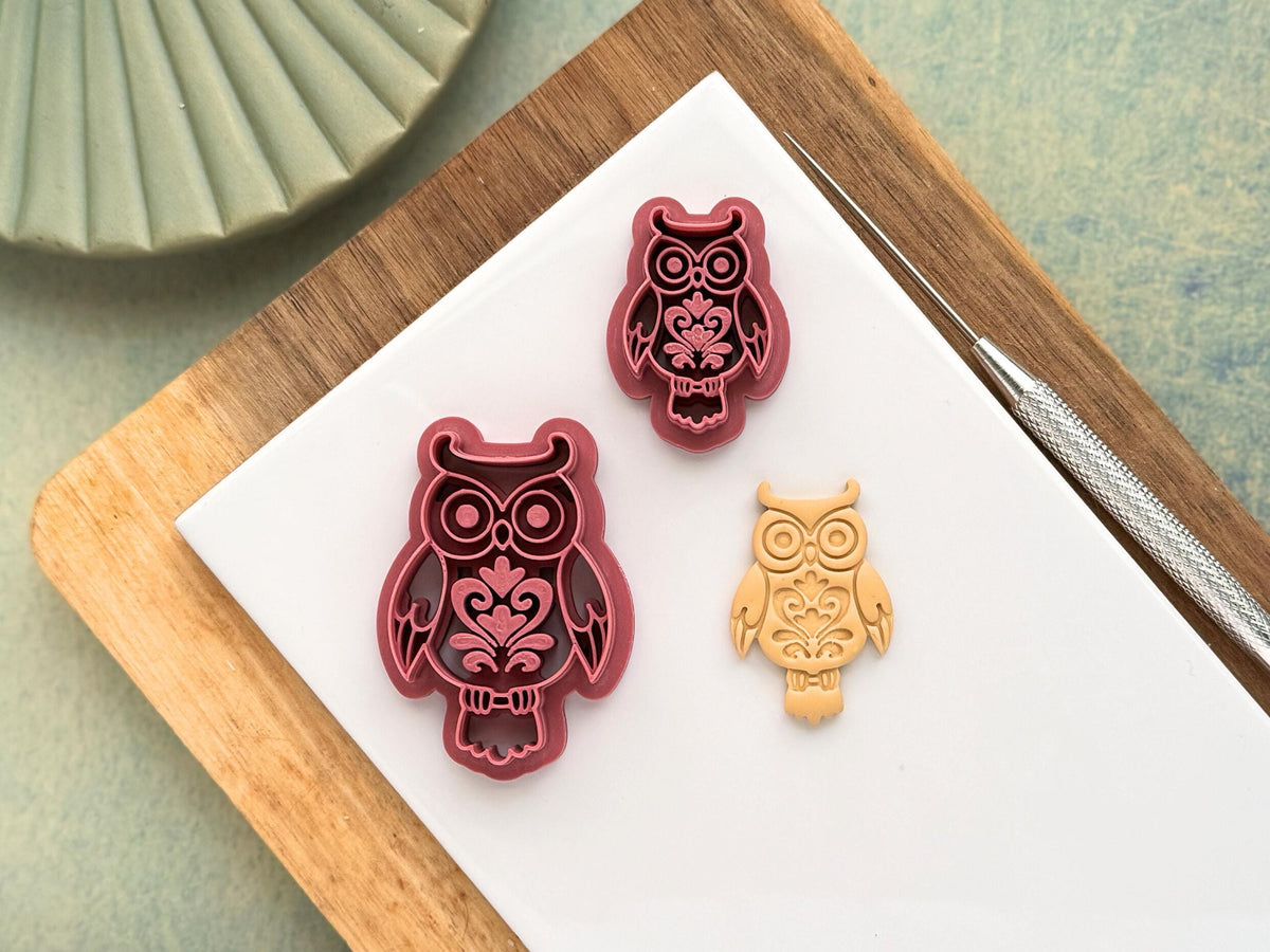 Pink decorative boho horned owl clay cutter in small and large sizes with floral style patterns. Next to the cutters is a beige polymer clay cut out sample
