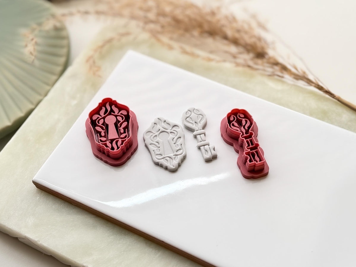 Tilted view of key and lock clay earring cutters and gray polymer clay cut out samples to show detail depth