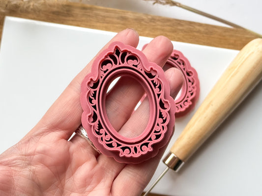 Decorative gilded vintage style picture frame polymer clay cutter being held in a hand
