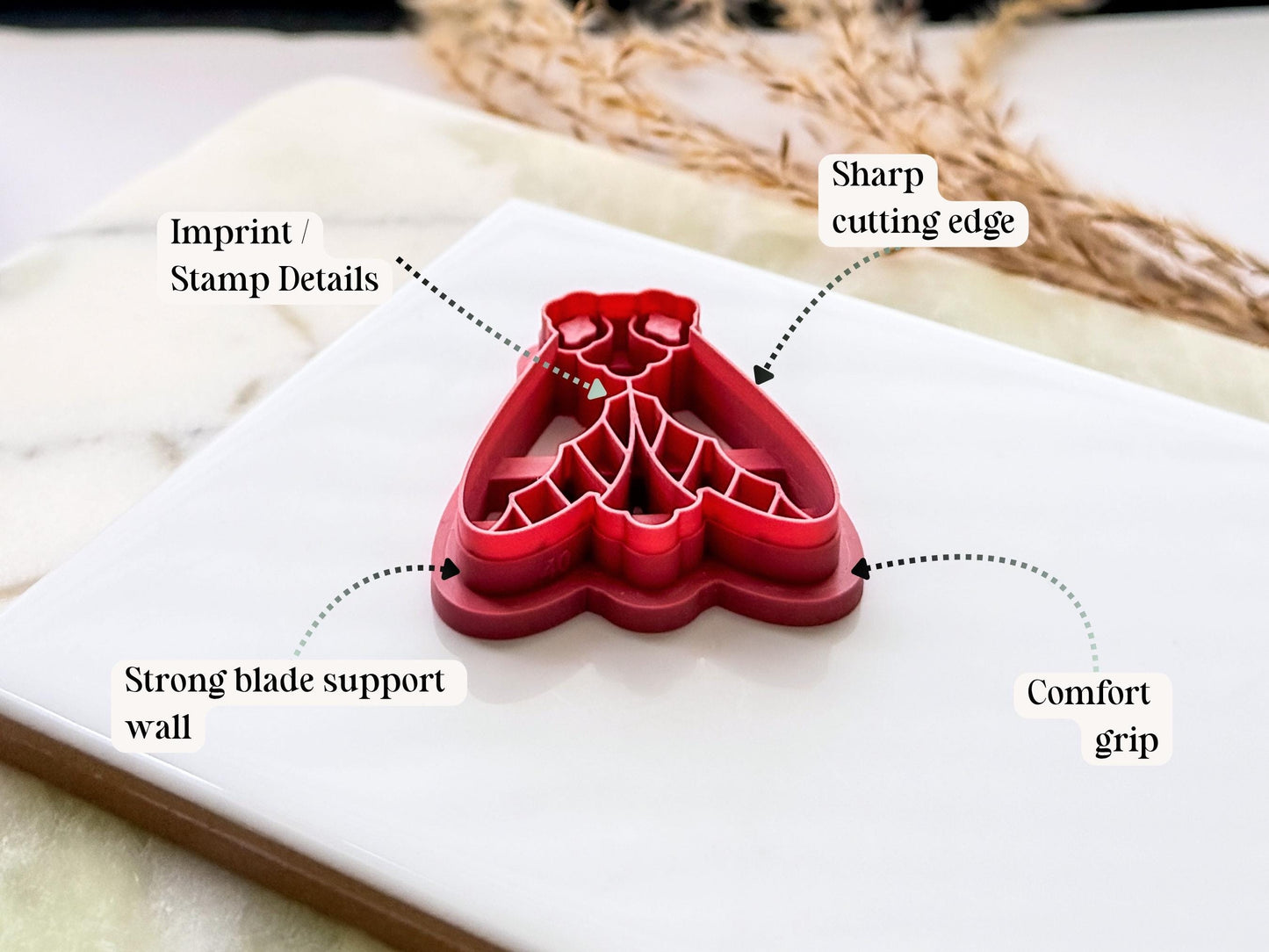 Pink garden moth clay cutter shown from the side to demonstrate the sharp blade edge, sturdy support wall, detailed imprint stamp and ergonomic grip. UK-made polymer clay and fondant crafting tool.