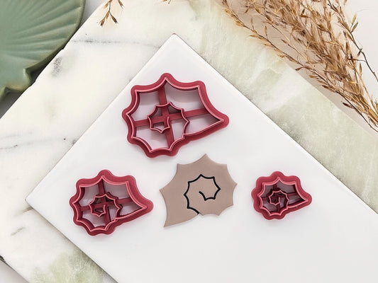 Various sizes of clay cutter in the shape of a spiky sea snail shell featuring a spiral centre. They are arranged on a white baking tile.
