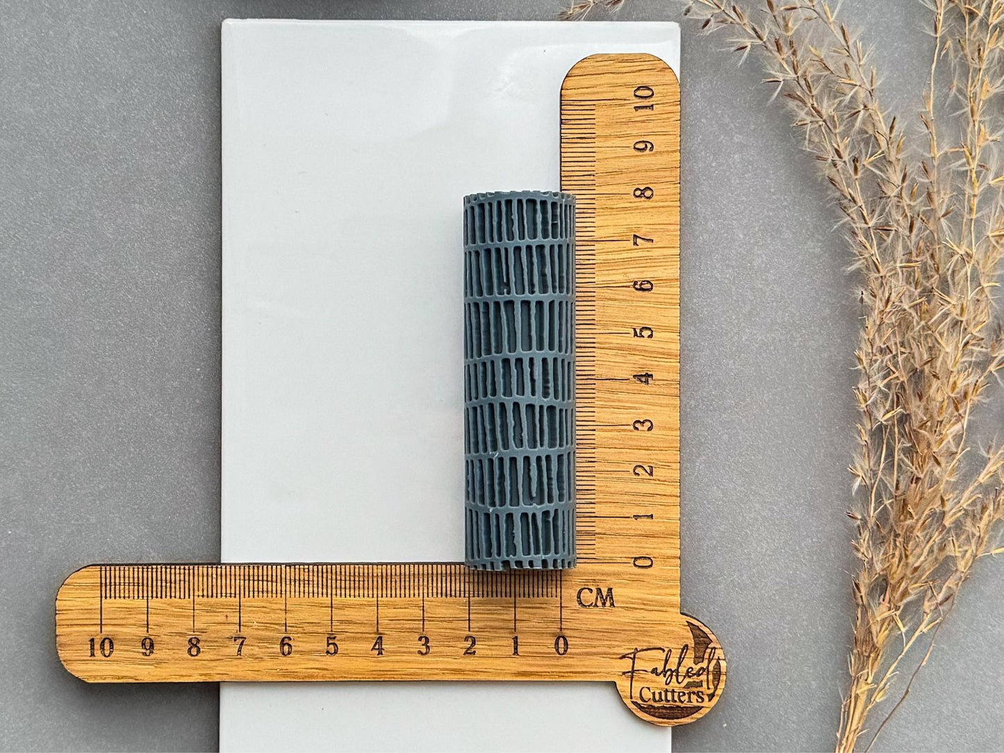 Size reference photo of linear brick texture roller with centimetre ruler for polymer clay.