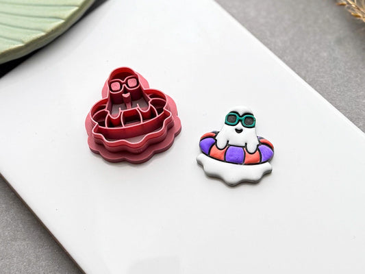 Angled view of a summer ghost pool float polymer clay cutter displayed beside a finished polymer clay ghost earring.