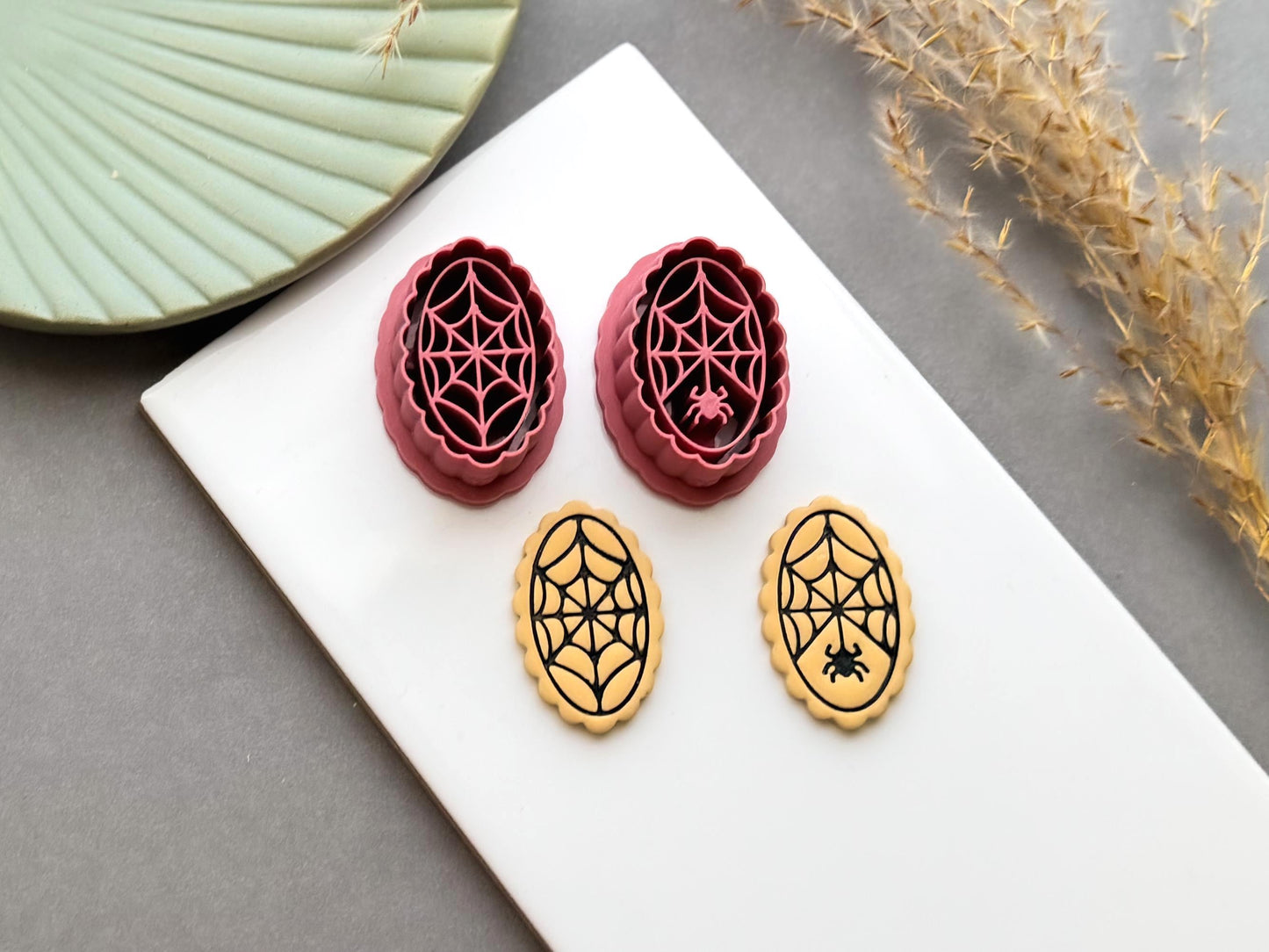 Spider web polymer clay cutters displayed alongside matching finished clay embellishments, featuring intricate web designs with and without small spiders, perfect for Halloween, gothic and spooky clay projects.