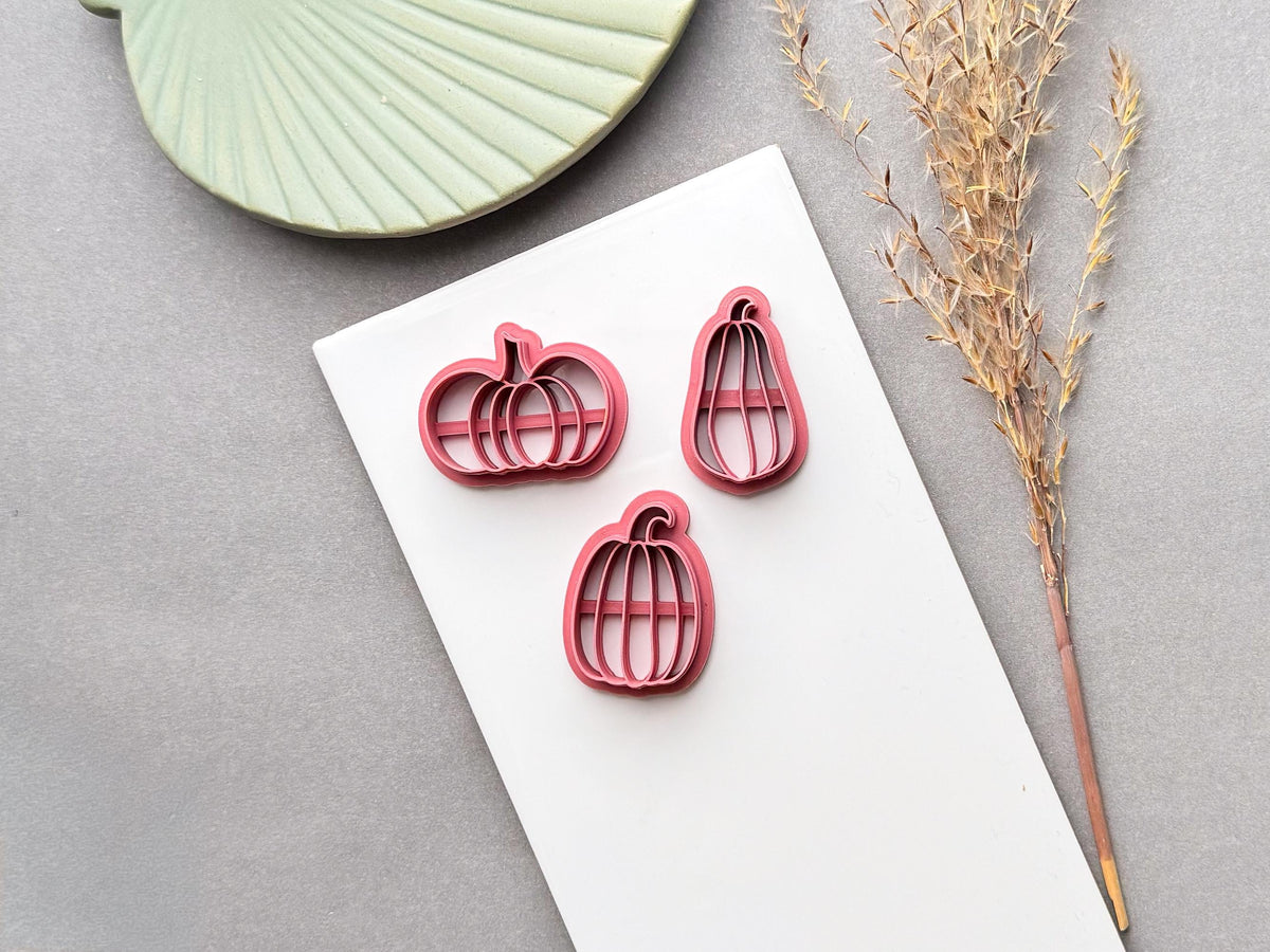 Pumpkin polymer clay cutters in three sizes, featuring segmented pumpkin designs with curved stems and internal support bars, displayed on a white surface.