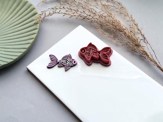 Ornamental fish polymer clay cutter featuring folk art details shown beside a lavender polymer clay cut-out.