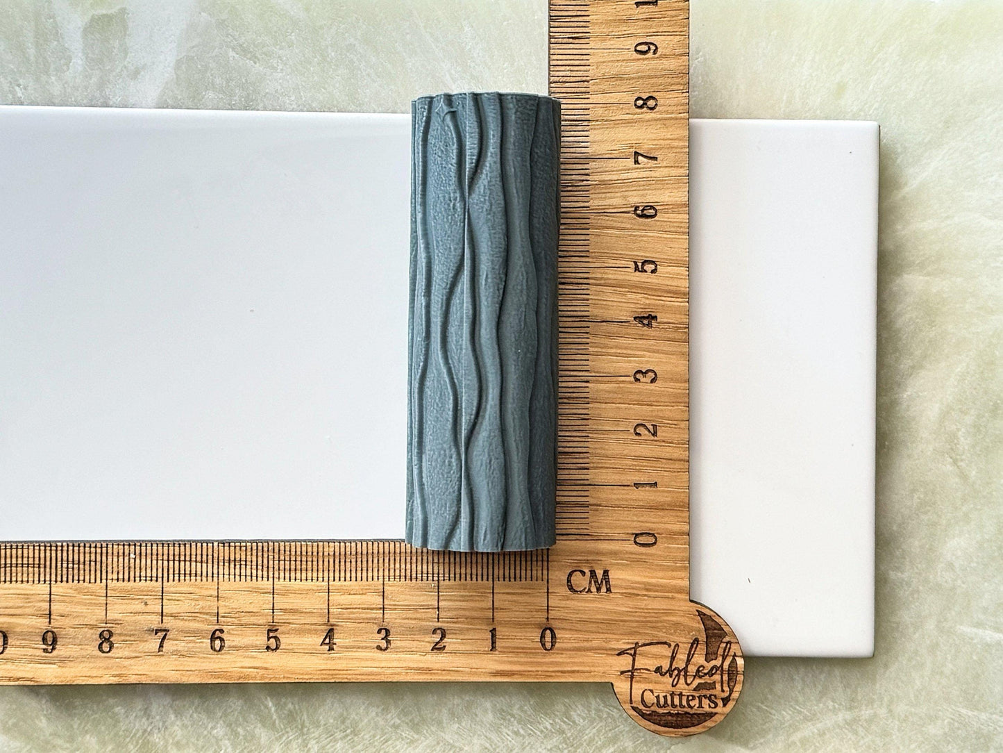 Grey wavy patterned resin texture roller against a ruler to display size
