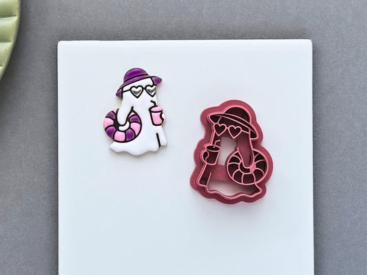 Summer ghost polymer clay cutter with beach accessories shown alongside a matching clay impression. The design includes a sun hat, heart sunglasses, drink and inflatable swim ring for Summerween jewellery and craft projects.