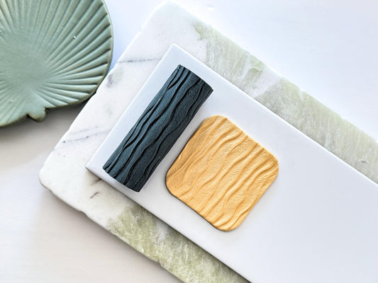 Sandy beach patterned texture roller and polymer clay sample slab on a white tile