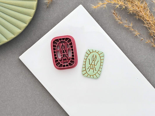 Beetle polymer clay cutter displayed beside a matching finished polymer clay embellishment featuring a simple beetle motif with an Art Deco-inspired geometric border.