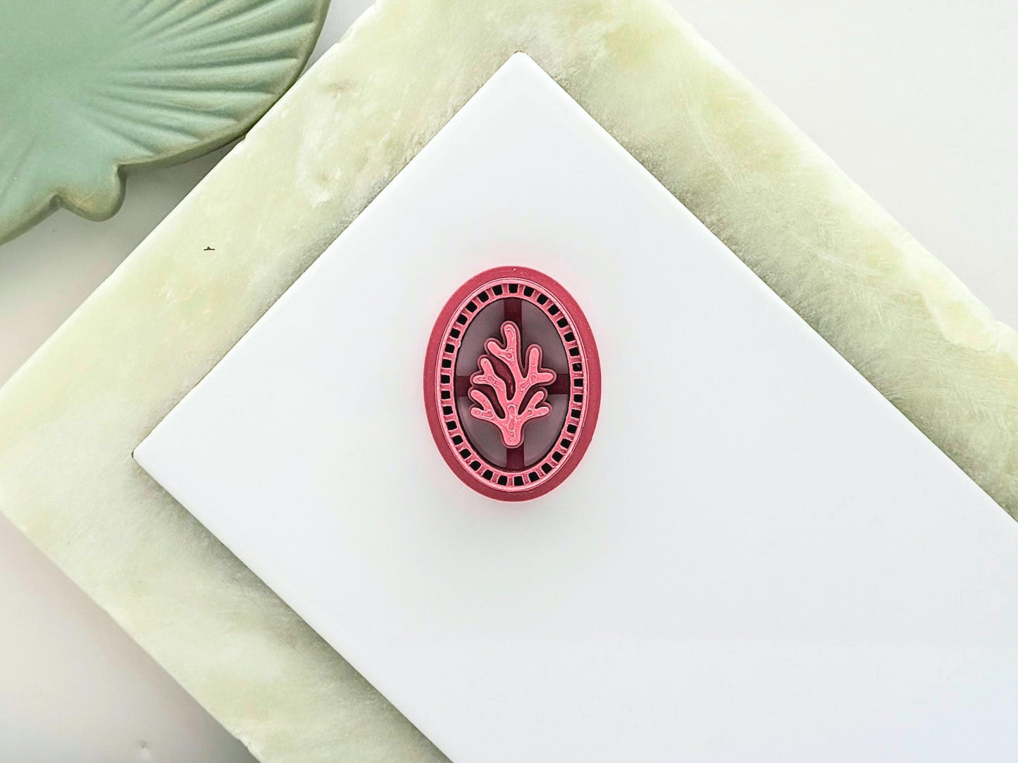 oval frame clay cutter with large coral stamp detail in the middle and decorative frame