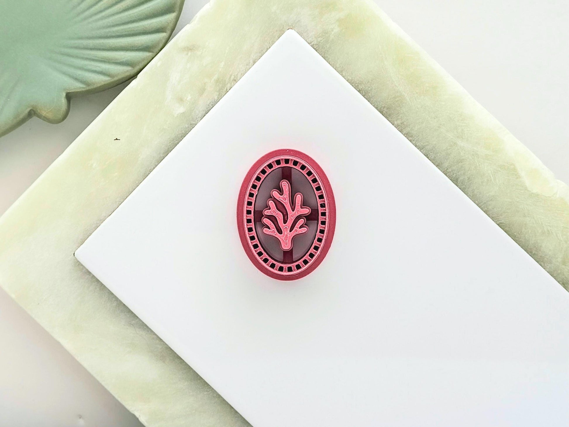 oval frame clay cutter with large coral stamp detail in the middle and decorative frame