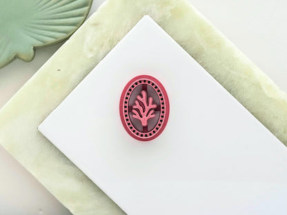 oval frame clay cutter with large coral stamp detail in the middle and decorative frame