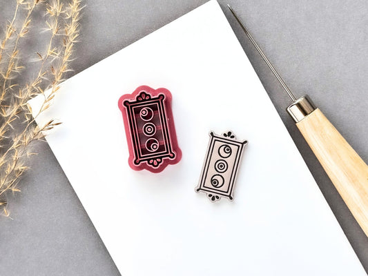 Rectangle frame polymer clay cutter featuring three eyeball details arranged vertically within an ornate rectangular border, shown beside a matching finished cream polymer clay cut-out. Pink 3D-printed cutter displayed on a white surface.