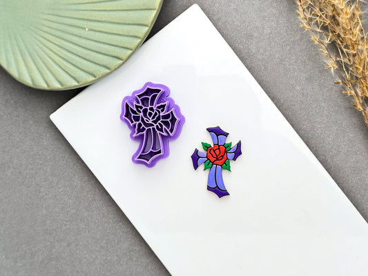 Purple stained glass cross polymer clay cutter with a rose design beside a finished stained glass style cross clay embellishment.