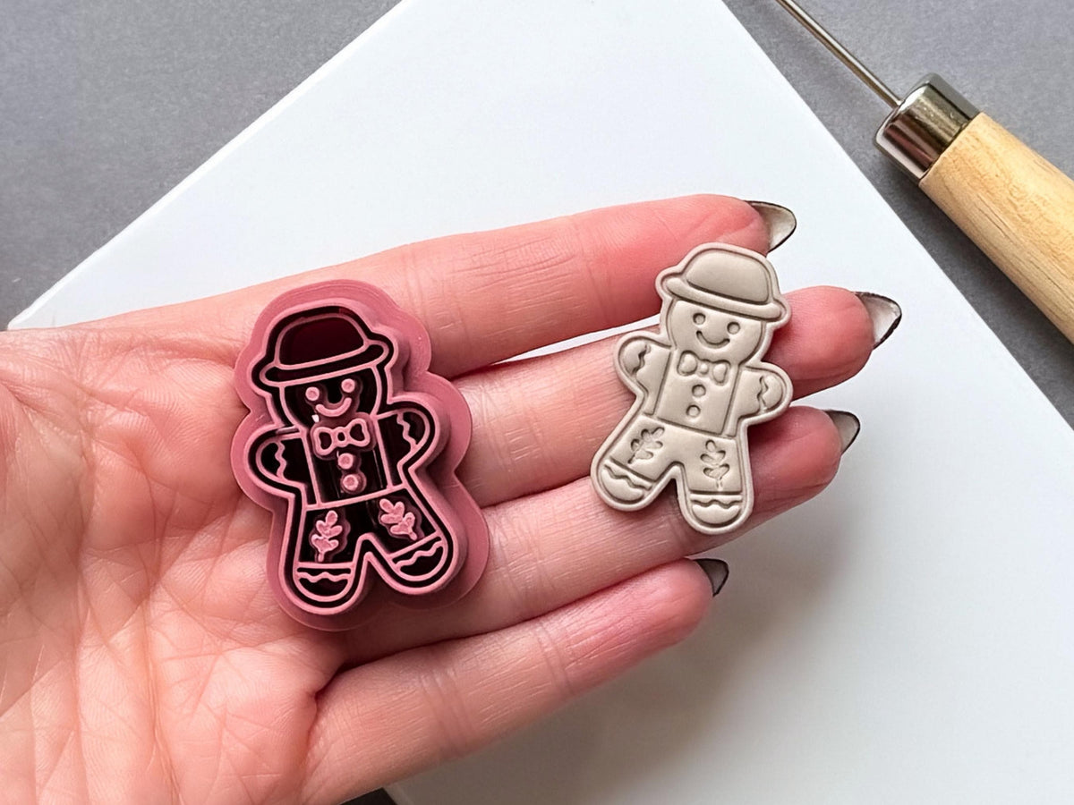 Vintage folk art gingerbread man polymer clay cutter and sample cut out held in hand for scale