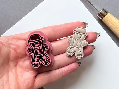 Vintage folk art gingerbread man polymer clay cutter and sample cut out held in hand for scale