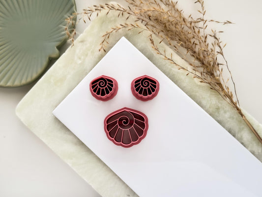 Seashell shaped clay cutters with swirl detail in dark pink colour. One large cutter and two mirrored cutters for making polymer clay earrings.