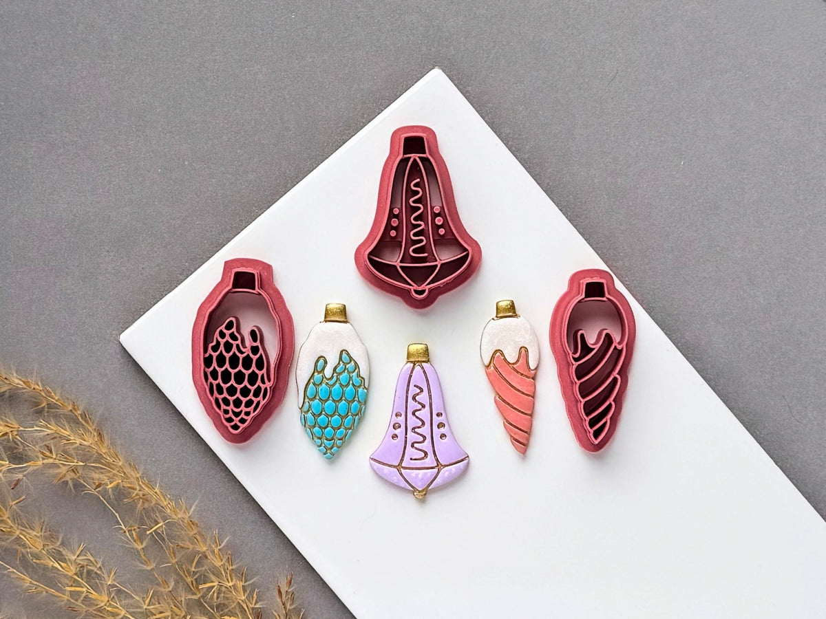 Christmas bauble polymer clay cutters displayed in three designs, featuring decorative teardrop ornaments with scalloped, spiral and geometric stamp details, alongside matching finished clay embellishments in colourful festive designs.