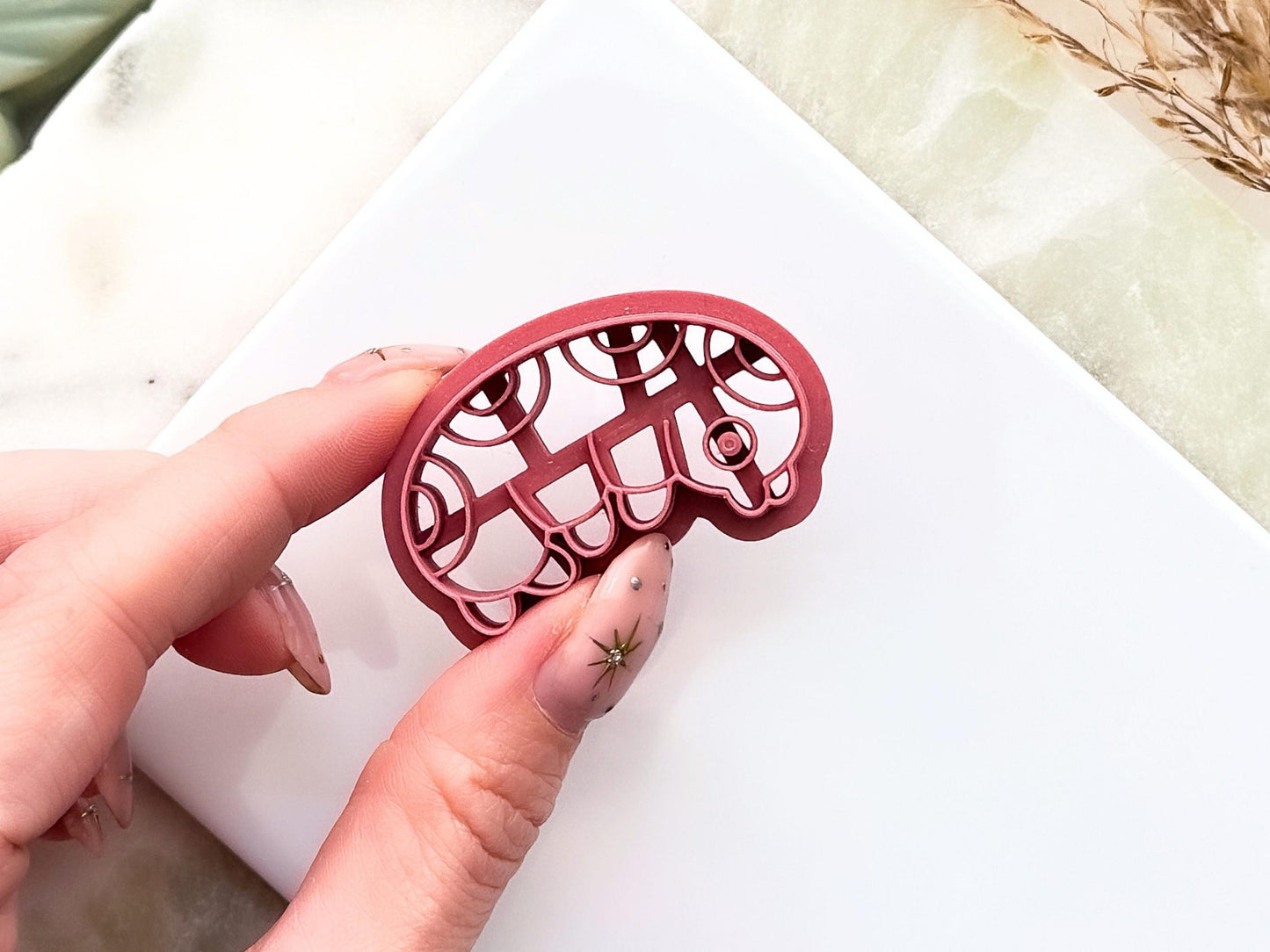 Close up of grub insect polymer clay shape cutter showing leg, eye and pattern details.